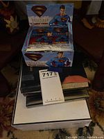 Photo showing Superman trading card box and packets on top of stacked books/folders.