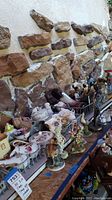 Wide view of multiple porcelain figurines and china pieces on shelving against stone wall