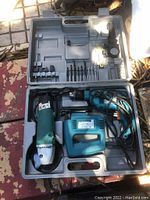 Power tools kit in gray plastic carrying case showing impact drill, jigsaw, angle sander, drill bits, and accessories