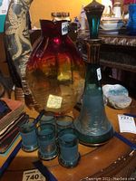 Photo showing tinted fish vase, green decanter with stopper, and six matching glasses grouped together on table.