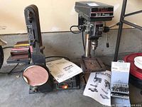 Wide view showing NuWay 5-speed drill press, Craftsman belt and disc sander, and accompanying manuals.
