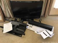 Photo showing Magnavox TV flat screen, Bose sound bar on original box, Simplicity articulating TV mount parts, instruction manuals.