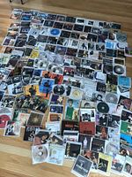 Wide view of approx 180 jazz CDs mostly without jewel cases laid out on floor, showing diverse album covers and disc cases in sleeves.