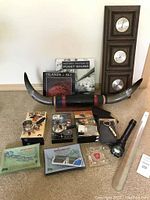 Full lot photo of wall mounted longhorn, books, VHS tapes, flashlight, shoehorn, wallets, ashtray set, and other miscellaneous items