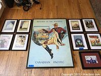 Overview photo showing all 9 framed items on a wooden floor, including 8 smaller Canadian Pacific travel poster/prints and one large "Resorts in the Rockies" print plus one autographed photograph.
