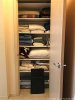 Shelves inside closet holding folded linens such as sheets, towels, and blankets.