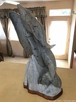 Front-angle view of sculpture showing two whales emerging from carved stone base