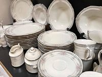 Overview photo showing multiple stacks of plates, cups, saucers, serving bowls and various accessories laid out on a surface.