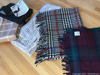 Four blankets arranged on floor showing patterns and textures including plaid and zigzag, and the American Express bag.