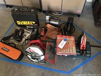 Full lot of power tools and accessories including saws, drills, sander, parts and cases on concrete floor