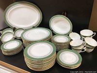Full set shown including stacked plates, cups, and serving platters on display table