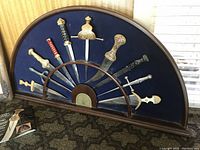 Full view of the ten cutters in semicircular wood display case against felt backing