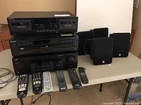 Overview photo showing Sony cassette deck, Sony CD player, JVC stereo receiver stacked together on a table with four Boston HS 40 speakers and five remote controls laid out in front.