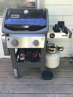 Front full view of Weber Spirit II gas barbecue grill with propane tank attached (tank not included in sale) and two control knobs visible.