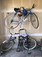 Two Schwinn bicycles mounted and standing in garage, Yakima rack on floor, two helmets hung on top bike