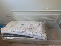 Wool blankets and bedspreads folded and stacked inside a plastic container showing fringed edges and fabric texture.