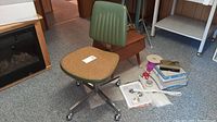 Green office chair with mustard seat and metal base next to wooden stool and sewing supplies on carpet