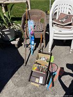 Photo of fishing rods, tackle box filled with lures, fishing accessories, fly swatters, and insect zappers arranged on outdoor pavement.