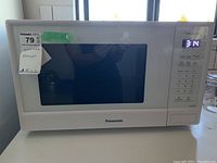 Front view of the Panasonic microwave oven showing the door and control panel, with a MaxSold sticker on the upper left corner.