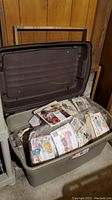 Open plastic bin filled with various colorful vintage sewing patterns, some still in plastic wrap.