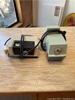 Two vintage electric pencil sharpeners, one green Welch Allyn and one white Brother, shown together with electrical cords visible.