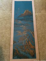 Full view of larger scroll showing beige border and blue panel with gold-painted landscape