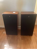 Two Yamaha NS-690 speakers front view showing wood veneer tops and black grilles on hardwood floor.