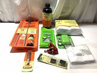 Photo showing full lot of Hoppe's firearm cleaning kit, cleaning fluids, Primos odor control sheets, soap bars, and cleaning patches arranged on table.