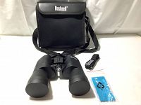 View of the binoculars with carrying case and accessories arranged on white background showcasing binoculars with lens caps on, carrying case behind, neck strap and cleaning cloth to side.