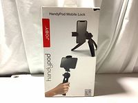 Front view of the product box showing Joby HandyPod Mobile Lock tripod with smartphone clamp and usage illustration.