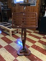 Full view of vintage handmade wooden music stand showing slatted desk and carved support base.