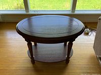 Top down view of the oval coffee table showing oval solid wood tabletop and lower shelf, with visible wood grain and finish.