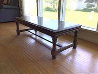 Side angle view showing turned legs and stretcher design on the vintage mid-century coffee table.