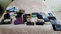 Photo showing many small bags and pouches laid out on a bed in various colors and materials.