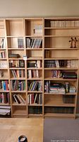Four Ikea Billy bookcases in birch veneer finish arranged side by side, filled with books and decorative items (contents not included in sale). Two wide units on left and right with two narrower units in middle.