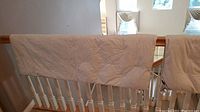 Five different blankets hung over a wooden railing, showing various sizes and quilting styles.