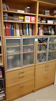 Galant combo bookcase with frosted glass doors and drawers, filled with books and items.
