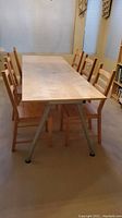 Rectangular wooden Ikea dining table with six matching wooden chairs surrounding it. Light wood finish with metal legs visible. Table surface has slight scratches.