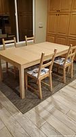 Ikea dining table and four chairs shown from side angle in kitchen space.
