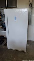 Front view of white upright freezer in garage setting