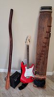 Full lot view: electric guitar, amplifier, didgeridoo, and kayagum standing upright