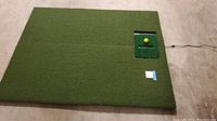 Artifical turf mat with integrated sensor and tee area visible from above, showing size and condition.