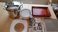 Overall view of soup pot, bowls, wooden tray, ceramic dish with trivet and street scene print on table