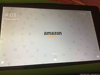 Amazon Fire tablet powered on displaying Amazon lock screen with logo and charging status.