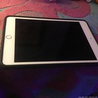 Front view of Apple iPad Mini 4 showing the screen, white bezel, and home button, device laid flat.