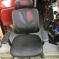 Front view of a black mesh desk chair with padded armrests and adjustable headrest.