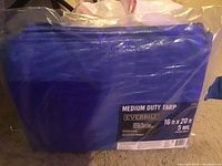 Blue EverBilt medium duty tarp folded and sealed in original clear plastic packaging with label showing size 16ft x 20ft and thickness 5 mil.