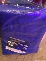Blue EverBilt medium duty tarp in original plastic bag, label visible showing size 20x30 ft and 5 mil thickness