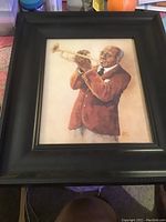 Full view of framed print with man playing trumpet in brown suit and black frame