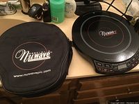 Photo of black NuWave carrying case placed on countertop next to the induction cooktop.